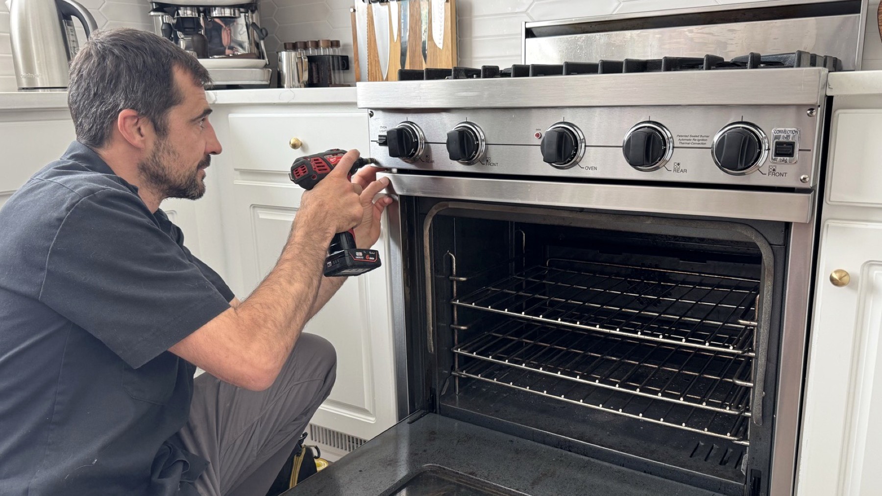 Technician repairing a stove and oven control panel with a drill